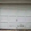 Worn and neglected garage door showing signs of damage and deterioration