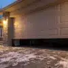 Residential garage door stopped mid-travel on a snowy Ottawa driveway