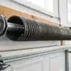 Close-up of a torsion spring mounted on a metal shaft