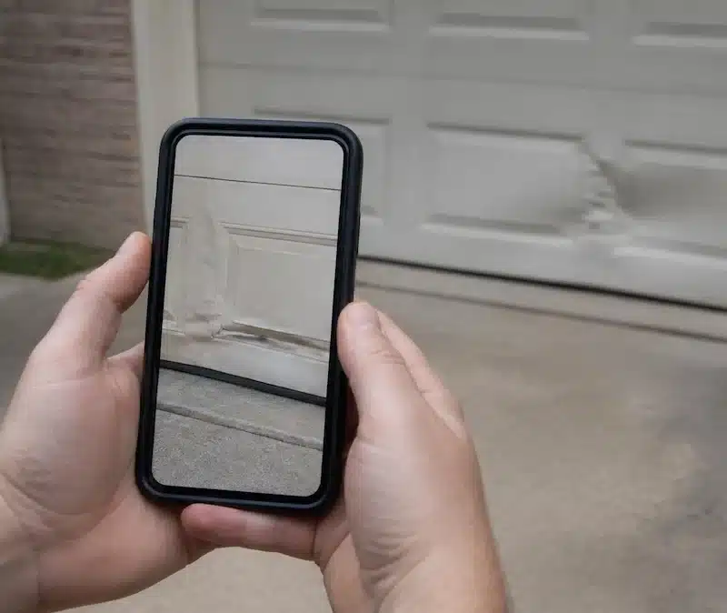 Homeowner documenting garage door damage for insurance claim