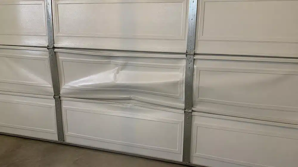 Dented and buckled panel on a residential garage door