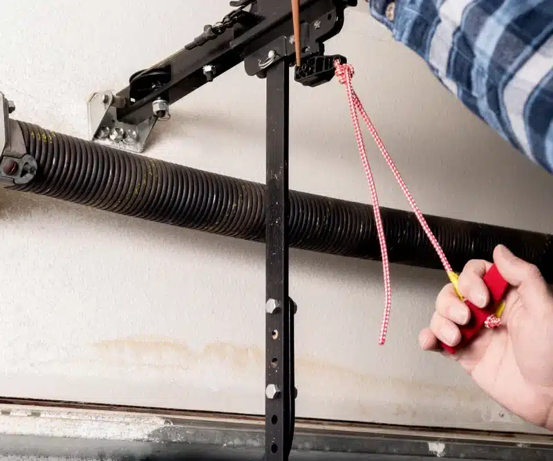Hand pulling the manual release cord on a garage door opener trolley