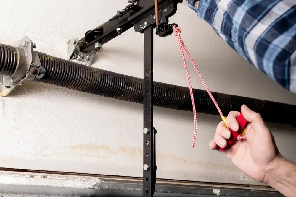 Hand pulling the manual release cord on a garage door opener trolley